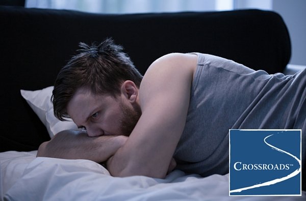 man laying in bed with alcohol disrupting his sleep