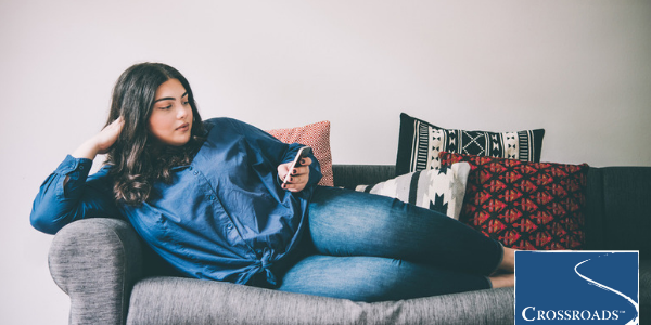 woman lounging on couch using phone to look up how to spot the signs of anorexia nervosa