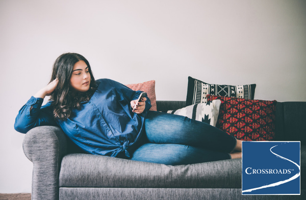 woman lounging on couch using phone to look up how to spot the signs of anorexia nervosa