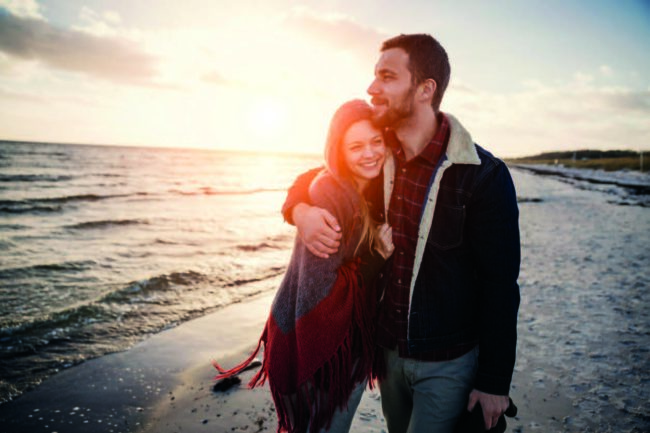 husband hugging smiling wife during walk on beach after recovery from mental health and substance use at Crossroads