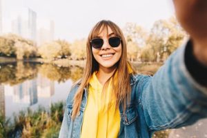 smiling woman taking selfie by pond happy with choosing a treatment program at Crossroads