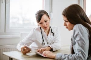 doctor showing teenage girl an infographic on understanding alcoholism