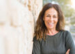 middle aged woman smiling next to rock wall because of benefits of residential treatment