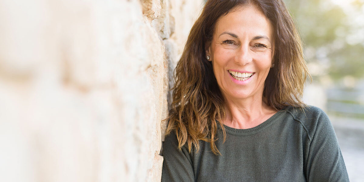 benefits of residential treatment middle aged woman smiling next to rock wall because of benefits of residential treatment