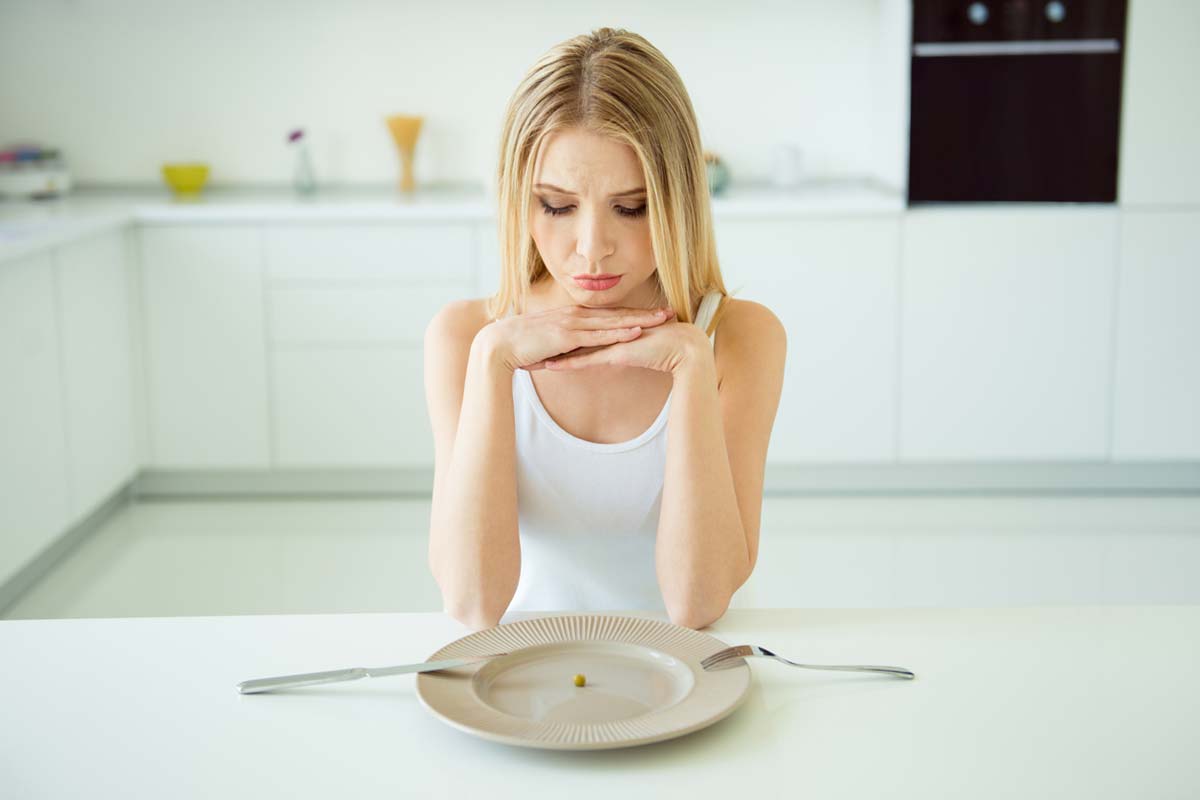common-eating-disorders woman with clear plate pondering common eating disorders
