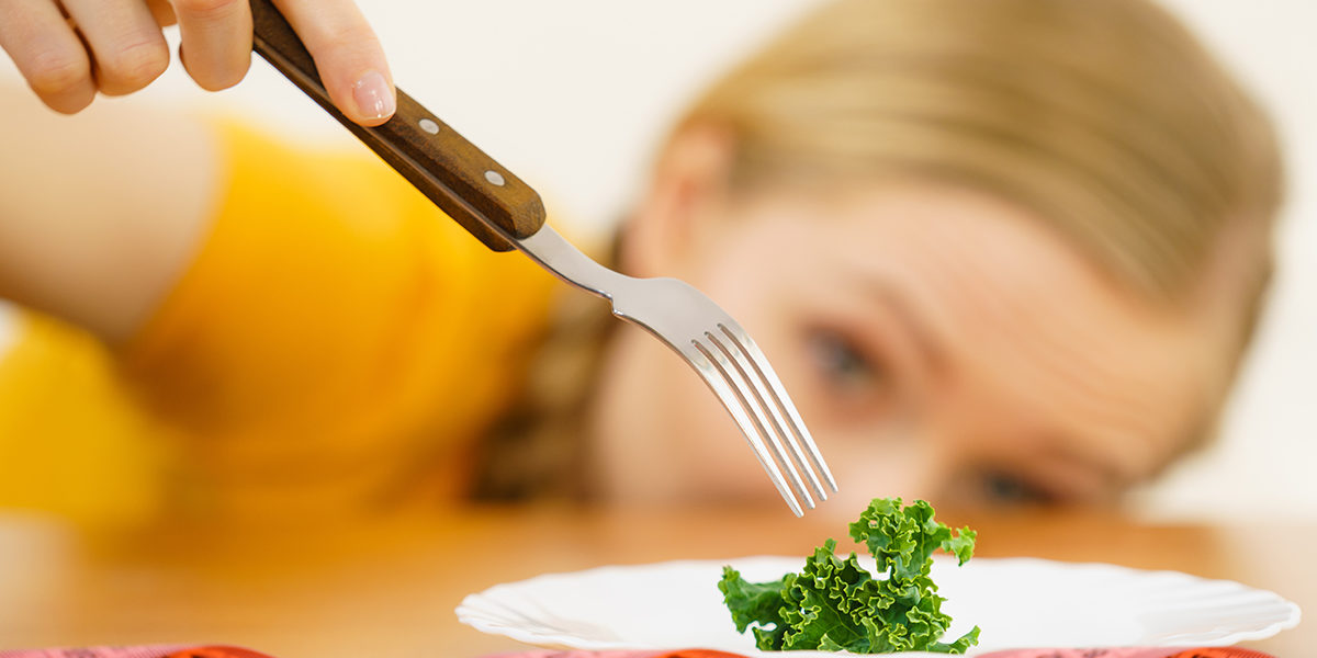 a woman prepares to eat a piece of lettuce as she considers a clean eating disorder