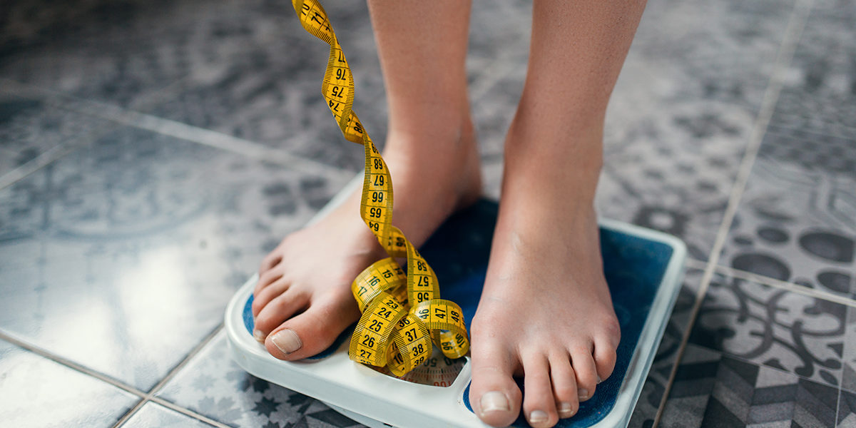a woman weighs herself as she considers eating disorder statistics