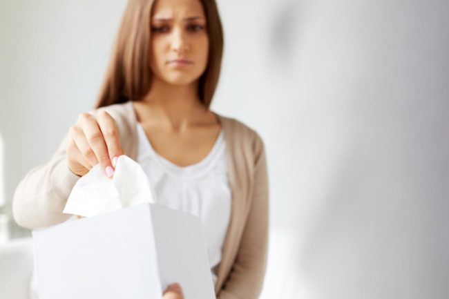 a woman takes a tissue as she considers the connection between substance use disorders and relationships