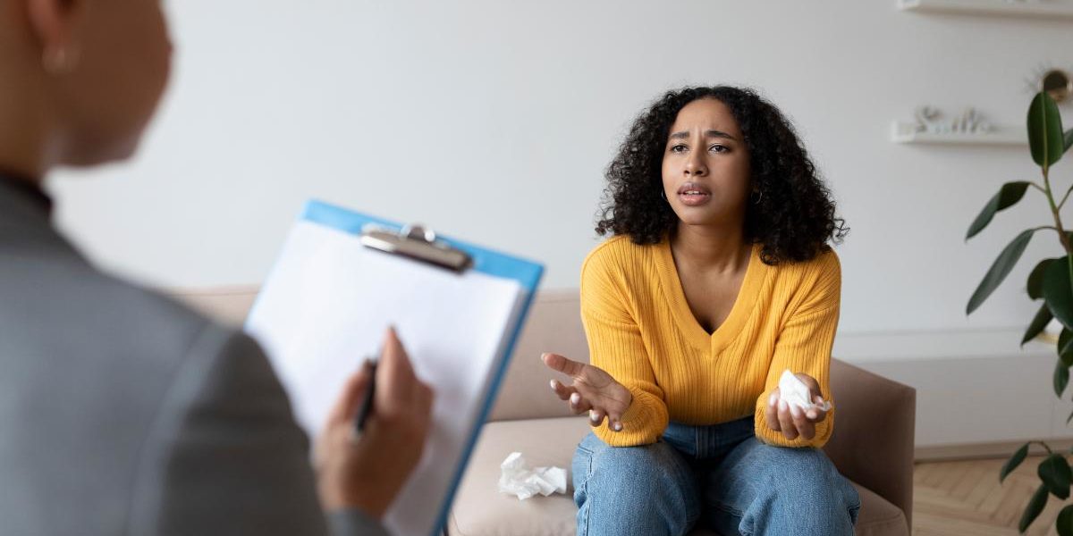 a woman talks to a therapist about trauma-informed alcohol addiction therapy