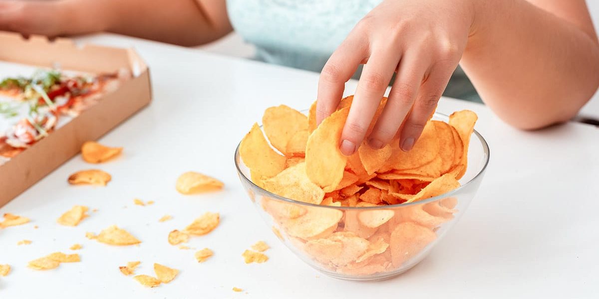 Why You Should Consider Binge Eating Disorder Treatment For Your Loved One a woman wonders why she consider binge eating disorder treatment as she eats chips