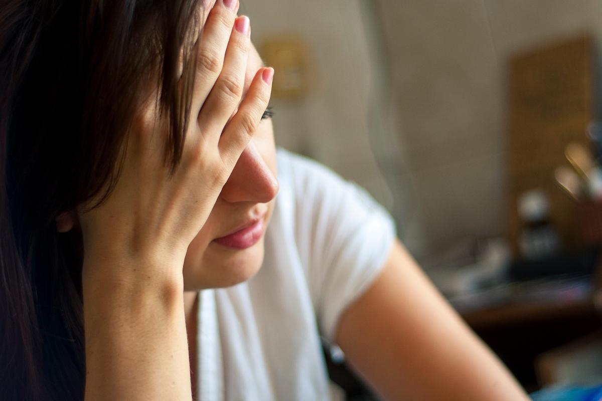 5 Symptoms of Heroin Addiction woman sitting with hand to her forehead learning about heroin addiction symptoms