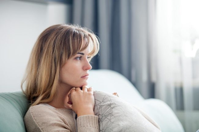 a woman sitting on couch thinking about needing help for borderline personality disorder